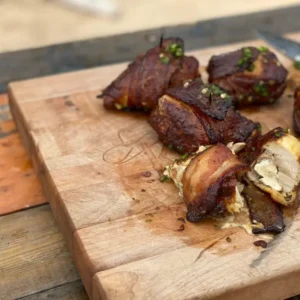 Bacon-wrapped chicken on a cutting board.