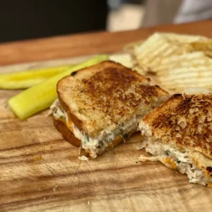 Grilled cheese sandwich with pickles and chips.