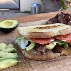 A sandwich cut in half on top of a wooden board.