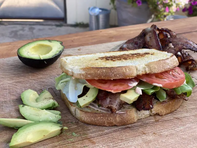 A sandwich cut in half on top of a wooden board.