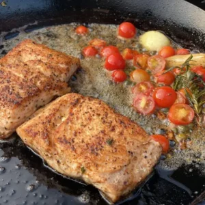 A pan with some meat and tomatoes on it