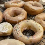 Glazed donuts with sprinkles on a rack.