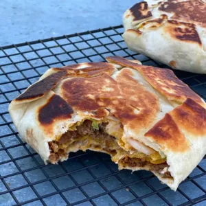 A close up of an open burrito on a grill