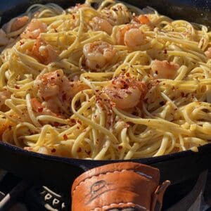 A pan of pasta with shrimp and cheese.