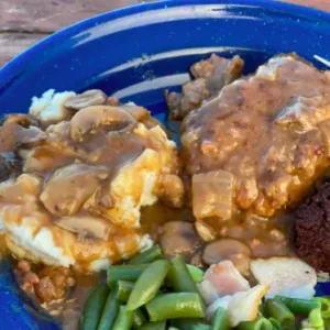 A blue bowl of food with meat, beans and mushrooms.