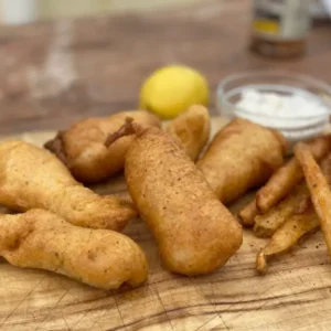 A wooden table topped with fish and fries.