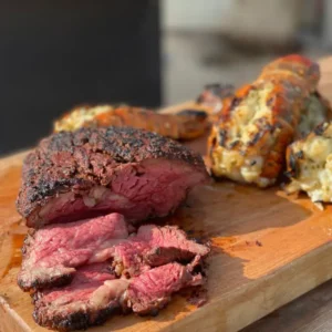 A steak and some other food on a cutting board.