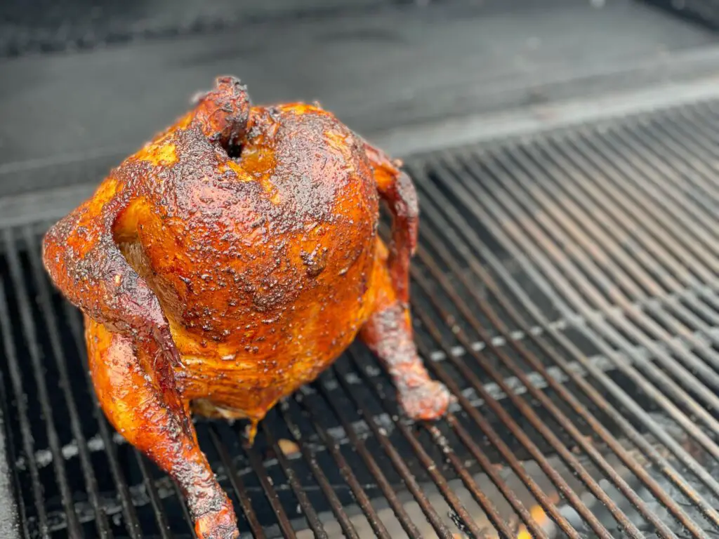 A chicken is sitting on the grill grate.