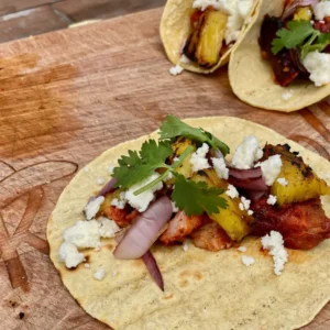 A wooden table topped with two tacos covered in toppings.