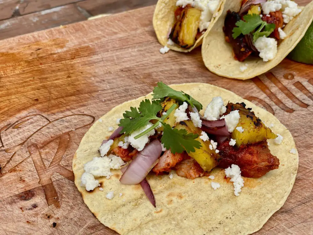 A wooden table topped with two tacos covered in toppings.