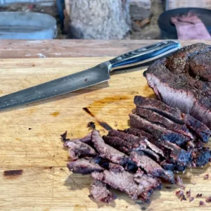 A knife and some meat on top of a cutting board.