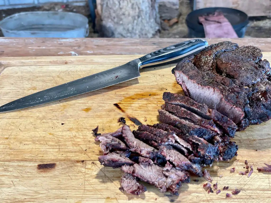 A knife and some meat on top of a cutting board.