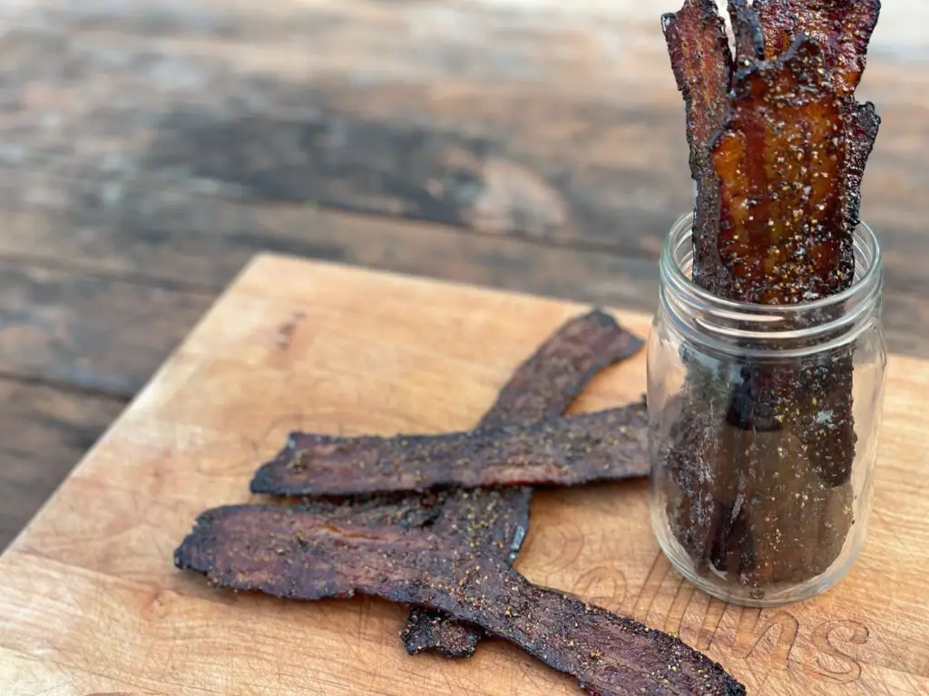 A jar of jerky sitting next to some other food.