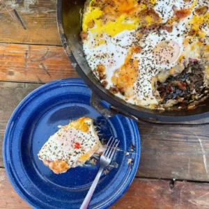 A blue plate and fork next to a pan of food.