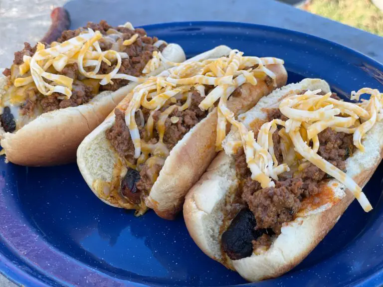 Three chili cheese dogs on a blue plate.