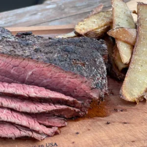 A close up of some meat and fries on a cutting board