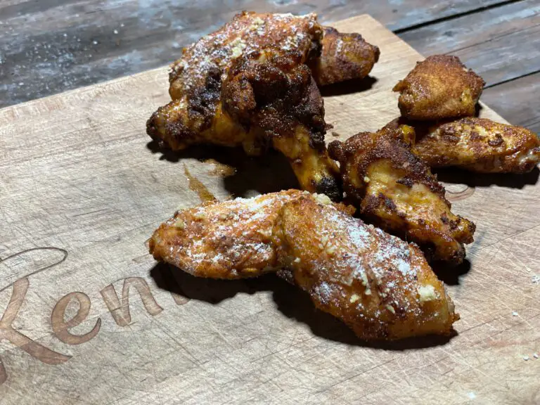 A wooden cutting board with some chicken wings on it