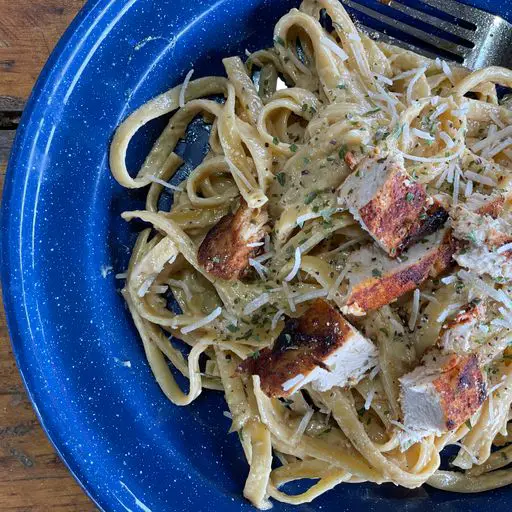 A blue plate topped with pasta covered in sauce.