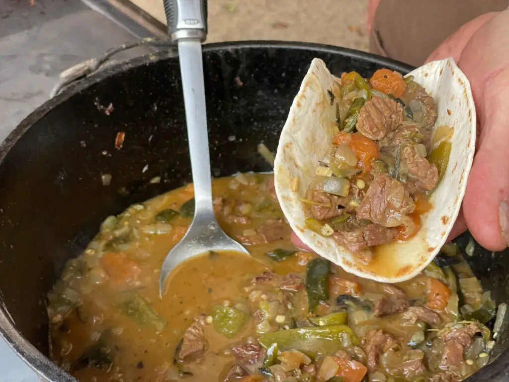 A person is stirring some stew in a pot