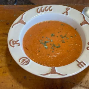 A bowl of soup on top of a wooden table.