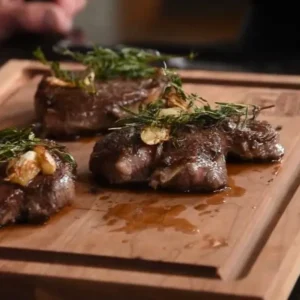 A wooden cutting board with some meat on it