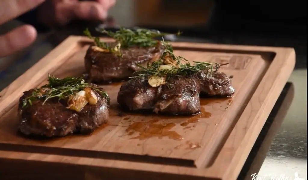 A wooden cutting board with some meat on it