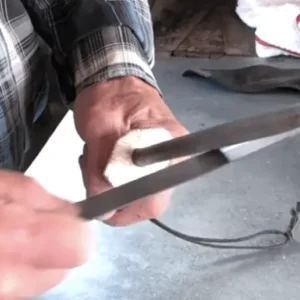 A person holding scissors cutting something with a knife.