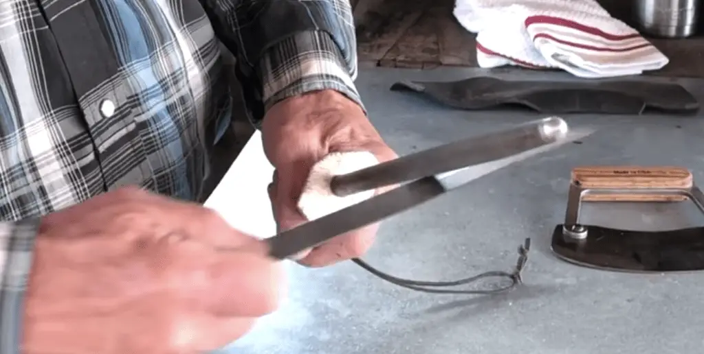 A person holding scissors cutting something with a knife.