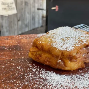 A pastry covered in powdered sugar on top of a wooden table.