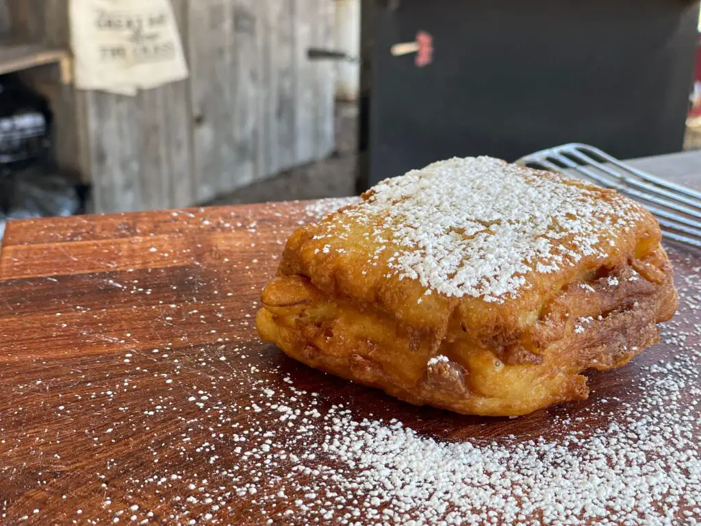 A pastry covered in powdered sugar on top of a wooden table.