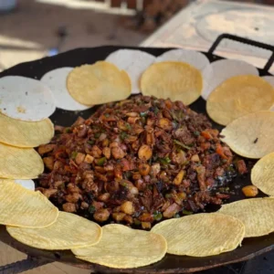 A pan of food with tortilla chips on the side.