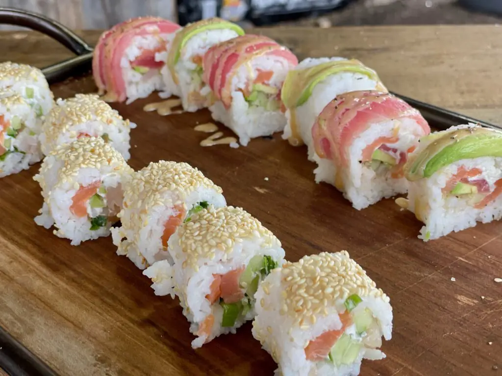 A wooden cutting board topped with sushi rolls.