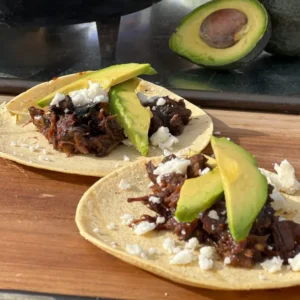 Two tacos are sitting on a wooden board.