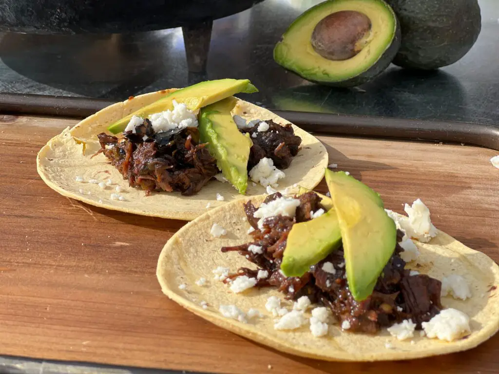 Two tacos are sitting on a wooden board.