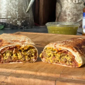 A burrito cut in half on top of a cutting board.