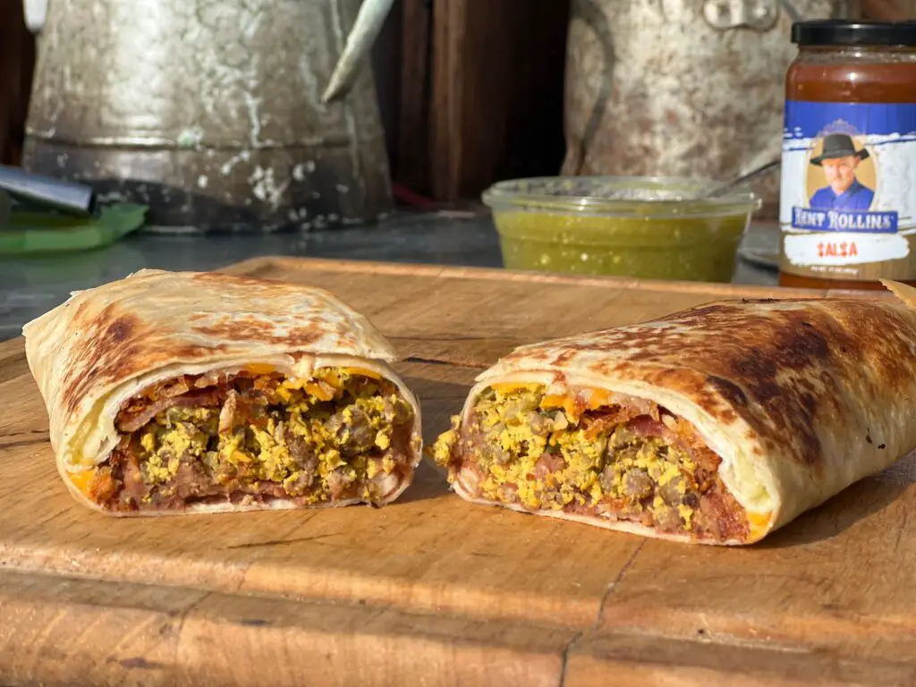 A burrito cut in half on top of a cutting board.