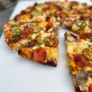 A pizza cut into slices on top of a white surface.