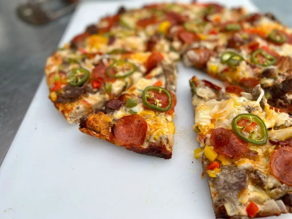 A pizza cut into slices on top of a white surface.