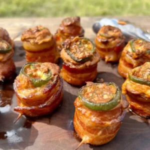 Bacon-wrapped jalapeno poppers on a wooden board.