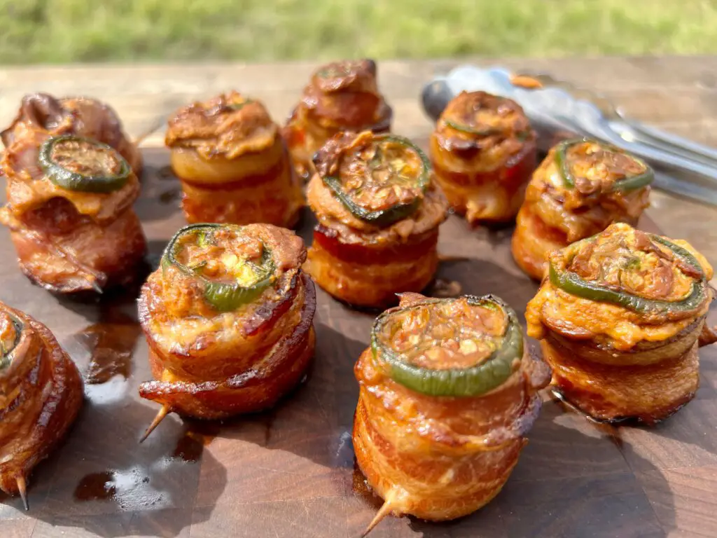 Bacon-wrapped jalapeno poppers on a wooden board.