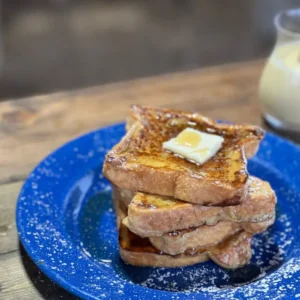 A blue plate with french toast and butter on it.