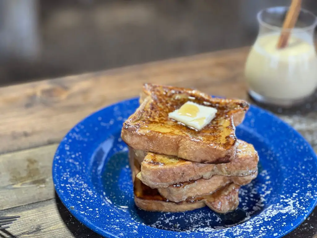 A blue plate with french toast and butter on it.