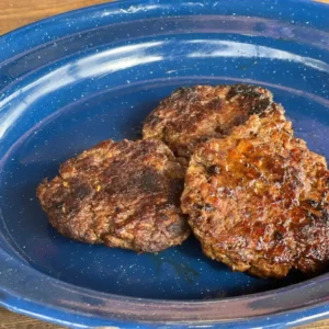 Three hamburger patties are sitting in a blue bowl.