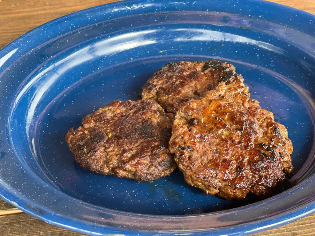 Three hamburger patties are sitting in a blue bowl.