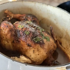 A chicken is cooked in a pot on the stove.