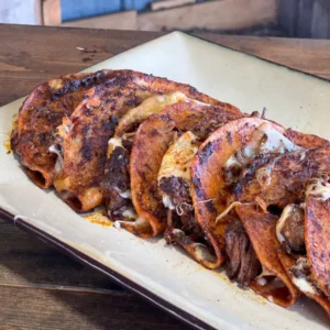 Cheesy beef enchiladas on a white plate.