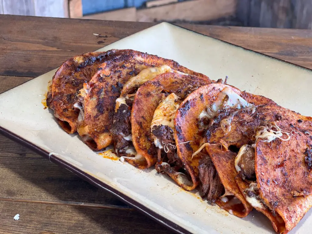 Cheesy beef enchiladas on a white plate.