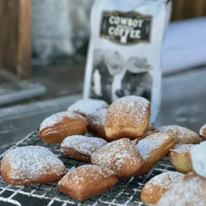 Powdered sugar beignets on wire rack.