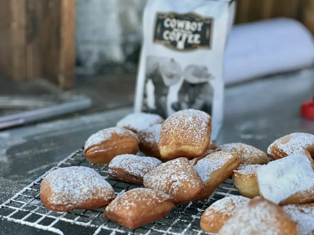 Powdered sugar beignets on wire rack.