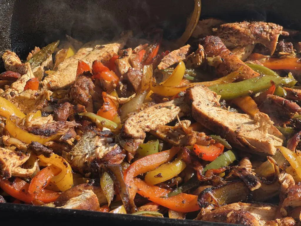 Chicken and peppers sizzling in a pan.